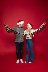 Full length portrait of a smiling young couple in christmas hats