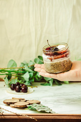 Superfoods concept: overnight chia pudding with fresh berries and whipped coconut cream in a hand. Selective focus. Place for text.
