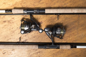 Two fishing rods on wooden background