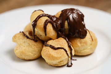 profiteroles covered with black chocolate on plate closeup