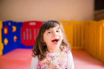 Portrait of little beautiful disabled girl who sitting in the game room and smiling