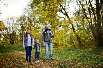Fototapeta premium Happy caucasian family of mom dad and little girl with boy at majestic autumn fall forest.