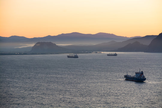 Nautical ships in a harbor at early morning. Tanker ship anchored in the sea bay.