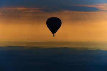 Aerial view of summer countryside during sunset with silhouette of hot air balloon