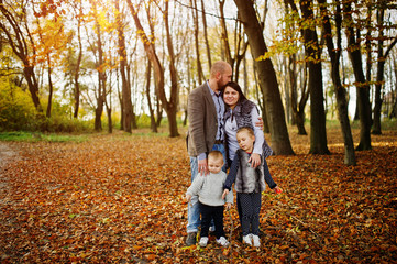 Naklejka premium Happy caucasian family of mom dad and little girl with boy at majestic autumn fall forest.