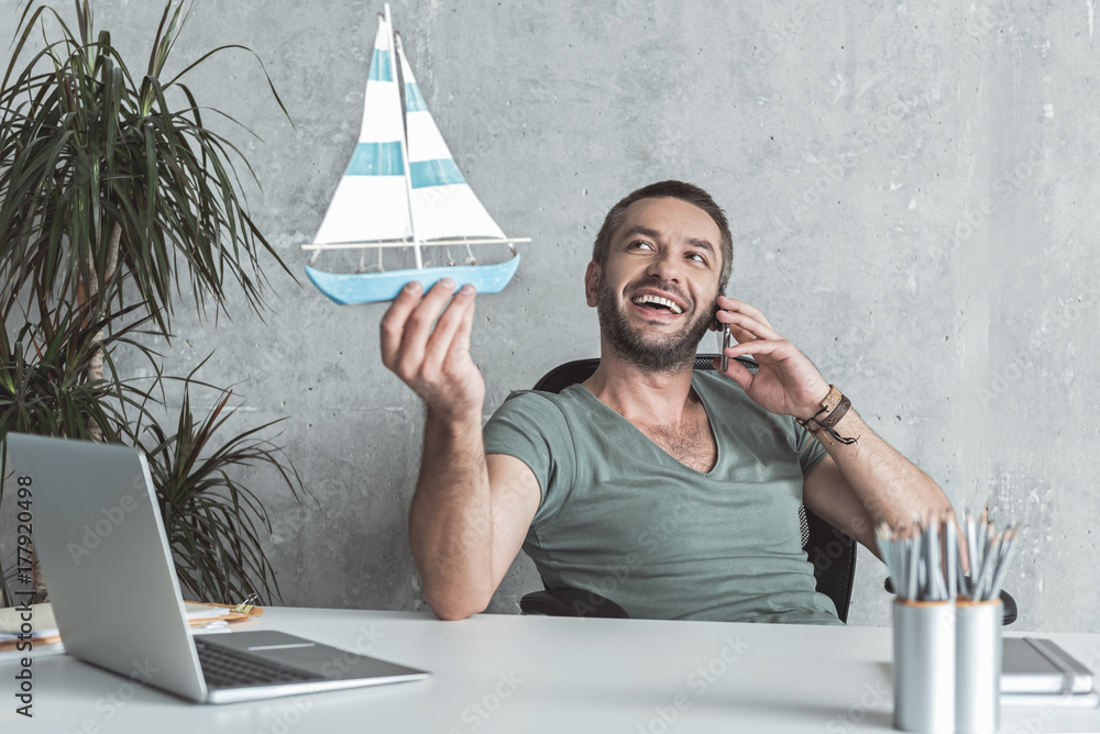 Wall mural Joyful cute man is having communication on smartphone