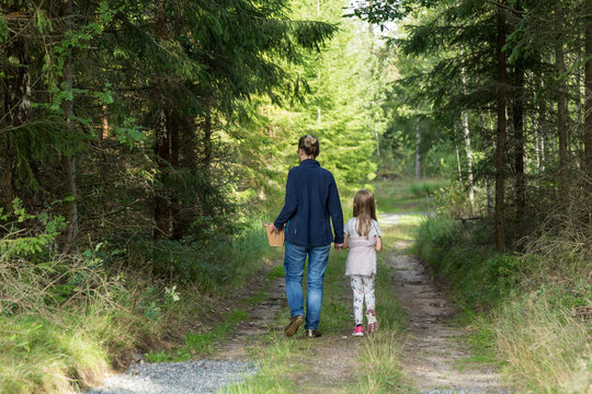 Barn och kvinna promenerar f&ouml;r att plocka svamp
