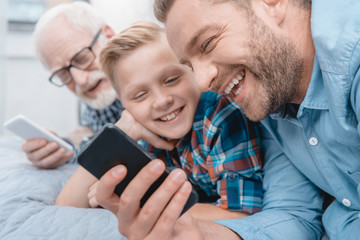 Happy family with smartphone on bed