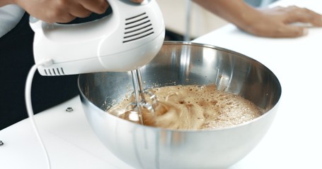 mixed race baker makes a cake. smash eggs