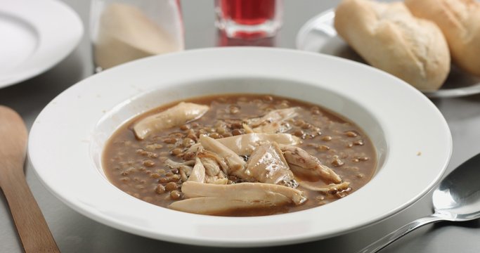 Delicious freshly made hot steaming chicken and lentil soup in a white wide-rimmed plate