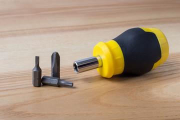 Screwdriver with three bits on wooden table