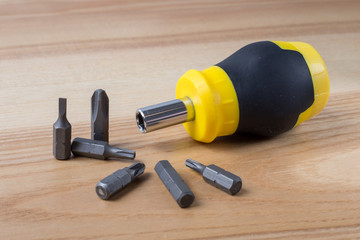 Screwdriver with set of bits on wooden table