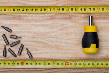 Aerial view screwdriver with measurement tape on wooden table ba