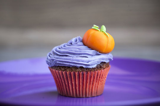 Halloween cupcake with a pumpkin on purple butter cream