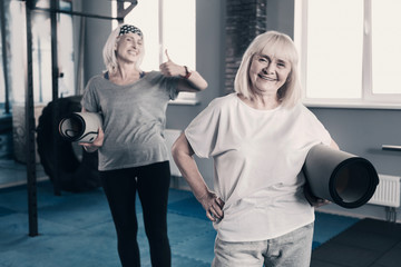 Cheerful elderly women posing with yoga mats