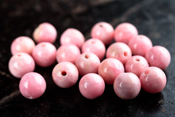 Collection of lovely pink round Rhodochrosite beads on black stone slate.