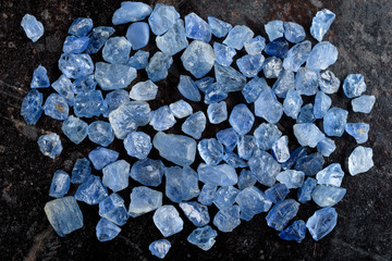 Collection of lovely blue rough and uncut sapphire gemstones on black stone slate. - 177924244
