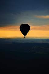 Aerial view of summer countryside during sunset with silhouette of hot air balloon