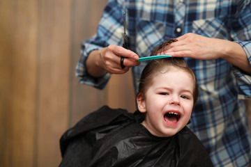 A little boy is trimmed in the hairdresser's bright emotions on 