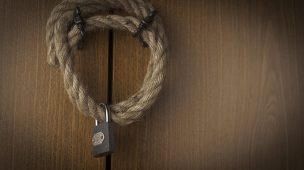 Closed lock on a rope against the background of wooden doors