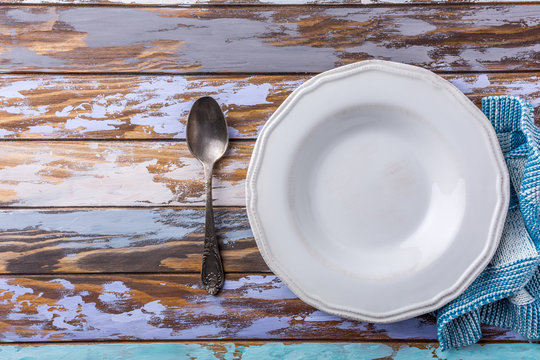 White empty plate on old wooden table, background concept blue, top view with copy space.