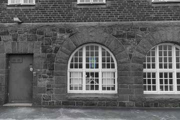 An old bricked house in black and white and a faded Swedish flag in yellow and blue