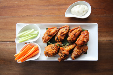 Buffalo wings barbecue chicken with carrots  and cucumbers on wood background