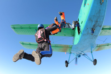 Skydivers are jumping out of a biplane.