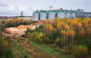 Fototapeta na wymiar Construction Natural Gas storage tanks and oil tank in industrial plant. Cloudy rainy weather and autumn forest