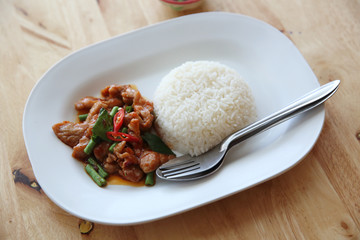 fried pork with thai curry and rice on wood background , Thai food