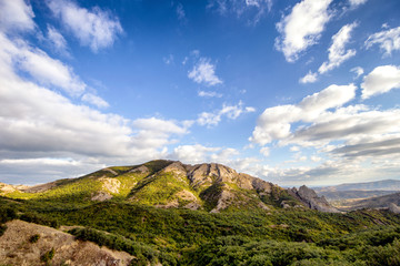 Ecological landscape with a mountain range and forest in a clear sunny autumn day. Blue sky with clouds