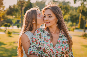 Love of mother and daughter. The daughter kisses Mom on the cheek. Happy family concept