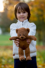 Cute preschool child, boy, holding little brown teddy bear in the park