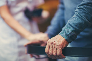 Fototapeta premium Cropped hands of nurse and senior woman holding walker
