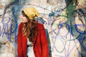 Modern girl in autumn seasson, walking around the city in the beautiful sunset light over graffiti wall background.