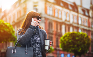 Urban scene, woman with coffee cup talking on mobile phone in city