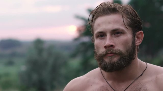 Portrait of free, beraded strong, blue-eyed man on nature. Slowly