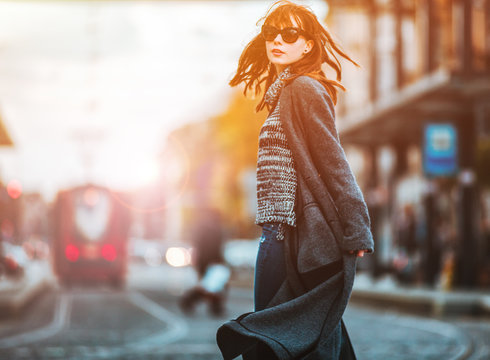 Trendy fashion woman in coat walking on the street, city scene