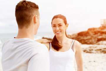 Runners. Young couple exercising and stertching on beach