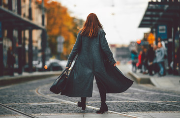 Trendy fashion woman in coat walking on the street, city scene