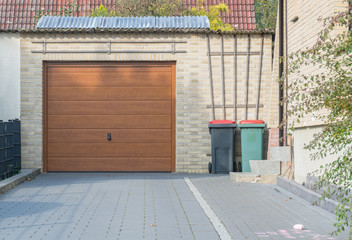 Braunes Garagentor und Mülleimer auf einem Garagenhof © GM Photography