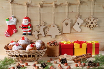 Christmas and New Year composition. Composition of Christmas and New Year decorations from plywood, a wicker basket with muffins, color gift boxes, nuts and fir branches on a wooden background.