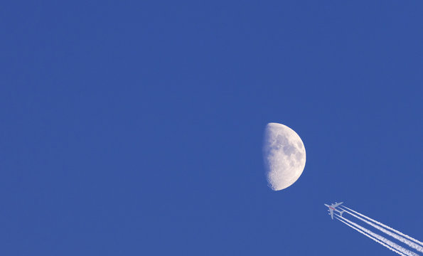 Moon and commercial airplane on blue sky background - Powered by Adobe