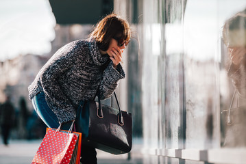 Shocked female on street looking at shopping window, shopaholic concept