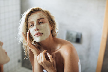 Woman Applying Face Mask - obrazy, fototapety, plakaty