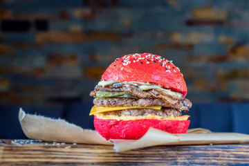 Restaurant burger with red bun on wooden board