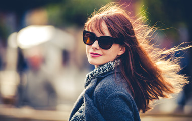 Close up fashion portrait of trendy woman in coat at the city