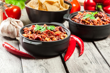Bowls of hot chili con carne with ground beef, beans, tomatoes and corn