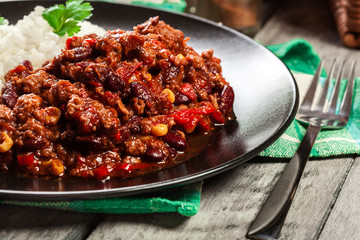 Hot chili con carne with ground beef, beans, tomatoes and corn served with rice