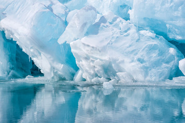 Blue growler piece of iceberg with reflection in calm water. Arctic ocean